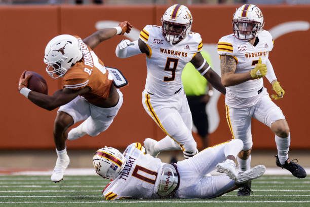 AUSTIN, TEXAS - SEPTEMBER 03: Bijan Robinson #5 of the Texas Longhorns is tripped up by Lu Tillery #0 of the Louisiana Monroe Warhawks in the first half at Darrell K Royal-Texas Memorial Stadium on September 03, 2022 in Austin, Texas. (Photo by Tim Warner/Getty Images)