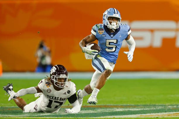 MIAMI GARDENS, FL - JANUARY 2: Dazz Newsome #5 of the North Carolina Tar Heels runs past the attempted tackle by Jaylon Jones #17 of the Texas A&amp;M Aggies at the Capital One Orange Bowl at Hard Rock Stadium on January 2, 2021 in Miami Gardens, Florida. (Photo by Joel Auerbach/Getty Images)