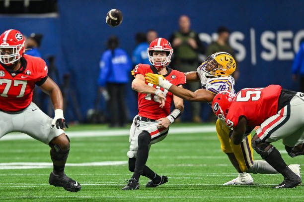 ATLANTA, GA  DECEMBER 03:  Georgia quarterback Stetson Bennett (13) throws a pass as he is hit by LSU defensive end BJ Ojulari (18) during the SEC Championship football game between the LSU Tigers and the Georgia Bulldogs on December 3rd, 2022 at Mercedes-Benz Stadium in Atlanta, GA.  (Photo by Rich von Biberstein/Icon Sportswire via Getty Images)