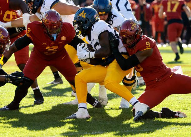 AMES, IA - NOVEMBER 5:  Running back Justin Johnson Jr. #26 of the West Virginia Mountaineers is tackled by defensive end Will McDonald IV #9 of the Iowa State Cyclones as defensive lineman MJ Anderson #3 of the Iowa State Cyclones defends in the first half of play at Jack Trice Stadium on November 5, 2022 in Ames, Iowa. (Photo by David K Purdy/Getty Images)