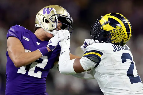 SEATTLE, WASHINGTON - OCTOBER 05: Will Johnson #2 of the Michigan Wolverines holds the mask of Denzel Boston #12 of the Washington Huskies at Husky Stadium on October 05, 2024 in Seattle, Washington. (Photo by Steph Chambers/Getty Images)