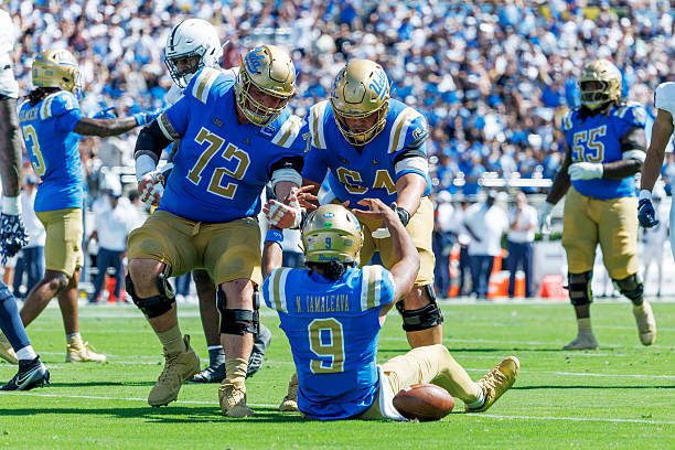 PASADENA, CA - OCTOBER 4, 2025: UCLA Bruins offensive lineman Garrett Digiorgio (72) and UCLA Bruins offensive lineman Sam Yoon (64) help up UCLA Bruins quarterback Nico Iamaleava (9) after the quarterback ran for extra yardage against Penn State at the Rose Bowl on October 4, 2025 in Pasadena, California.(Gina Ferazzi / Los Angeles Times via Getty Images)