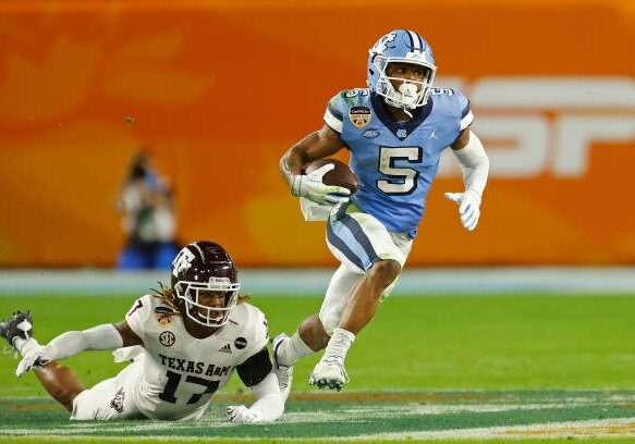 MIAMI GARDENS, FL - JANUARY 2: Dazz Newsome #5 of the North Carolina Tar Heels runs past the attempted tackle by Jaylon Jones #17 of the Texas A&amp;M Aggies at the Capital One Orange Bowl at Hard Rock Stadium on January 2, 2021 in Miami Gardens, Florida. (Photo by Joel Auerbach/Getty Images)