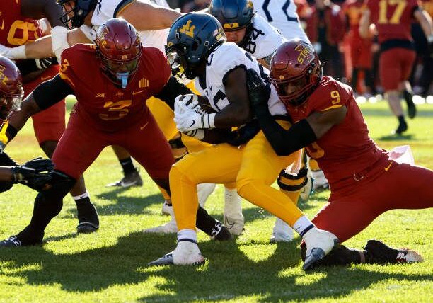 AMES, IA - NOVEMBER 5:  Running back Justin Johnson Jr. #26 of the West Virginia Mountaineers is tackled by defensive end Will McDonald IV #9 of the Iowa State Cyclones as defensive lineman MJ Anderson #3 of the Iowa State Cyclones defends in the first half of play at Jack Trice Stadium on November 5, 2022 in Ames, Iowa. (Photo by David K Purdy/Getty Images)