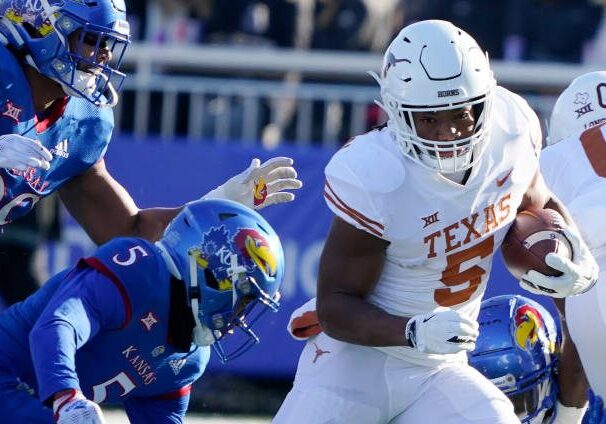 LAWRENCE, KANSAS - NOVEMBER 19: Running back Bijan Robinson #5 of the Texas Longhorns runs against safety O.J. Burroughs #5 and defensive lineman Malcolm Lee #99 of the Kansas Jayhawks first half at David Booth Kansas Memorial Stadium on November 19, 2022 in Lawrence, Kansas. (Photo by Ed Zurga/Getty Images)