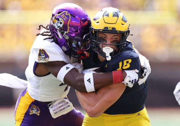 ANN ARBOR, MICHIGAN - SEPTEMBER 02: Colston Loveland #18 of the Michigan Wolverines battles for extra yards against Julius Wood #4 of the East Carolina Pirates after a first quarter catch at Michigan Stadium on September 02, 2023 in Ann Arbor, Michigan. (Photo by Gregory Shamus/Getty Images)