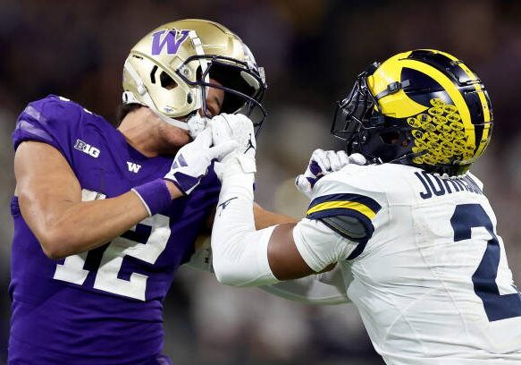 SEATTLE, WASHINGTON - OCTOBER 05: Will Johnson #2 of the Michigan Wolverines holds the mask of Denzel Boston #12 of the Washington Huskies at Husky Stadium on October 05, 2024 in Seattle, Washington. (Photo by Steph Chambers/Getty Images)