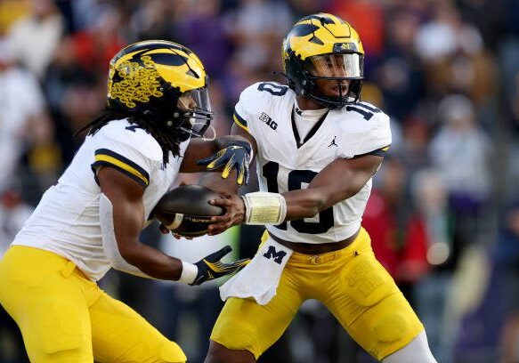 SEATTLE, WASHINGTON - OCTOBER 05: Alex Orji #10 hands the ball off to Donovan Edwards #7 of the Michigan Wolverines against the Washington Huskies at Husky Stadium on October 05, 2024 in Seattle, Washington. (Photo by Steph Chambers/Getty Images)