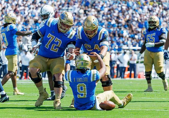 PASADENA, CA - OCTOBER 4, 2025: UCLA Bruins offensive lineman Garrett Digiorgio (72) and UCLA Bruins offensive lineman Sam Yoon (64) help up UCLA Bruins quarterback Nico Iamaleava (9) after the quarterback ran for extra yardage against Penn State at the Rose Bowl on October 4, 2025 in Pasadena, California.(Gina Ferazzi / Los Angeles Times via Getty Images)