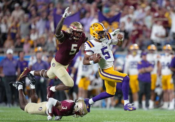 ORLANDO, FL - SEPTEMBER 03: LSU Tigers quarterback Jayden Daniels (5) runs past tackle attempt by Florida State Seminoles defensive back Kevin Knowles II (3) and Florida State Seminoles defensive lineman Jared Verse (5) during the Camping World Kickoff game between the LSU Tigers and the Florida State Seminoles, on Sunday, September 3, 2023 at Camping World Stadium in Orlando, Fla. (Photo by Peter Joneleit/Icon Sportswire via Getty Images)