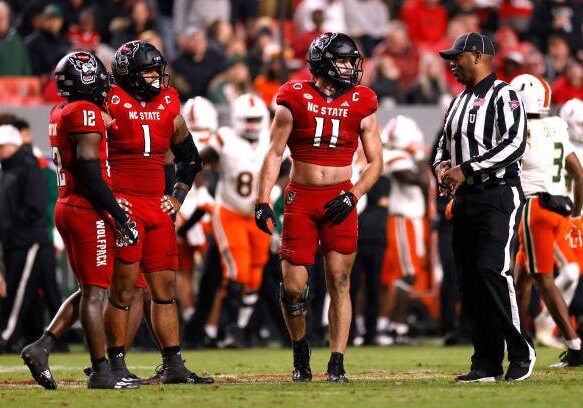 RALEIGH, NORTH CAROLINA - NOVEMBER 4: Davin Vann #1 and Payton Wilson #11 of the NC State Wolfpack listen to an official during the game against the Miami Hurricanes at Carter-Finley Stadium on November 4, 2023 in Raleigh, North Carolina. NC State won 20-6. (Photo by Lance King/Getty Images)